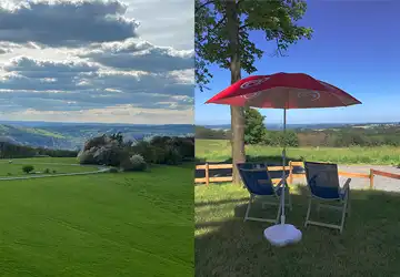 Sonnenliegen unter dem Sonnenschirm mit Blick auf grüne Wiesen.